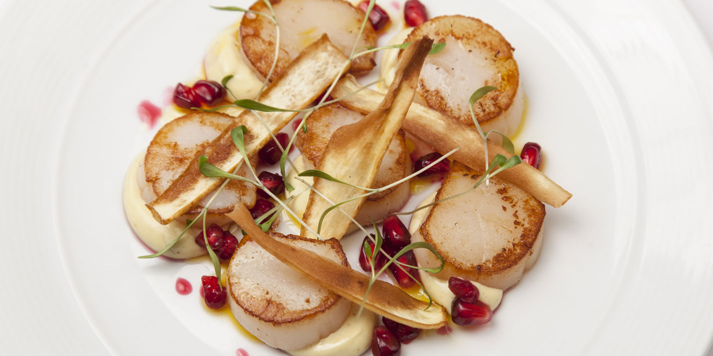 Scallops with curried parsnip purée, parsnip crisps and pomegranate