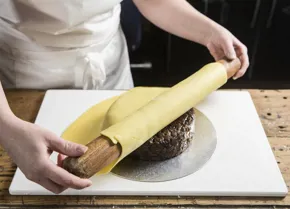 Fold the marzipan over the rolling pin and lay on to the cake
