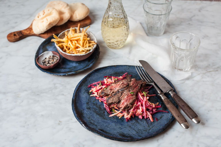 Marinated skirt steak on a fresh roots salad and crispy matchstick fries