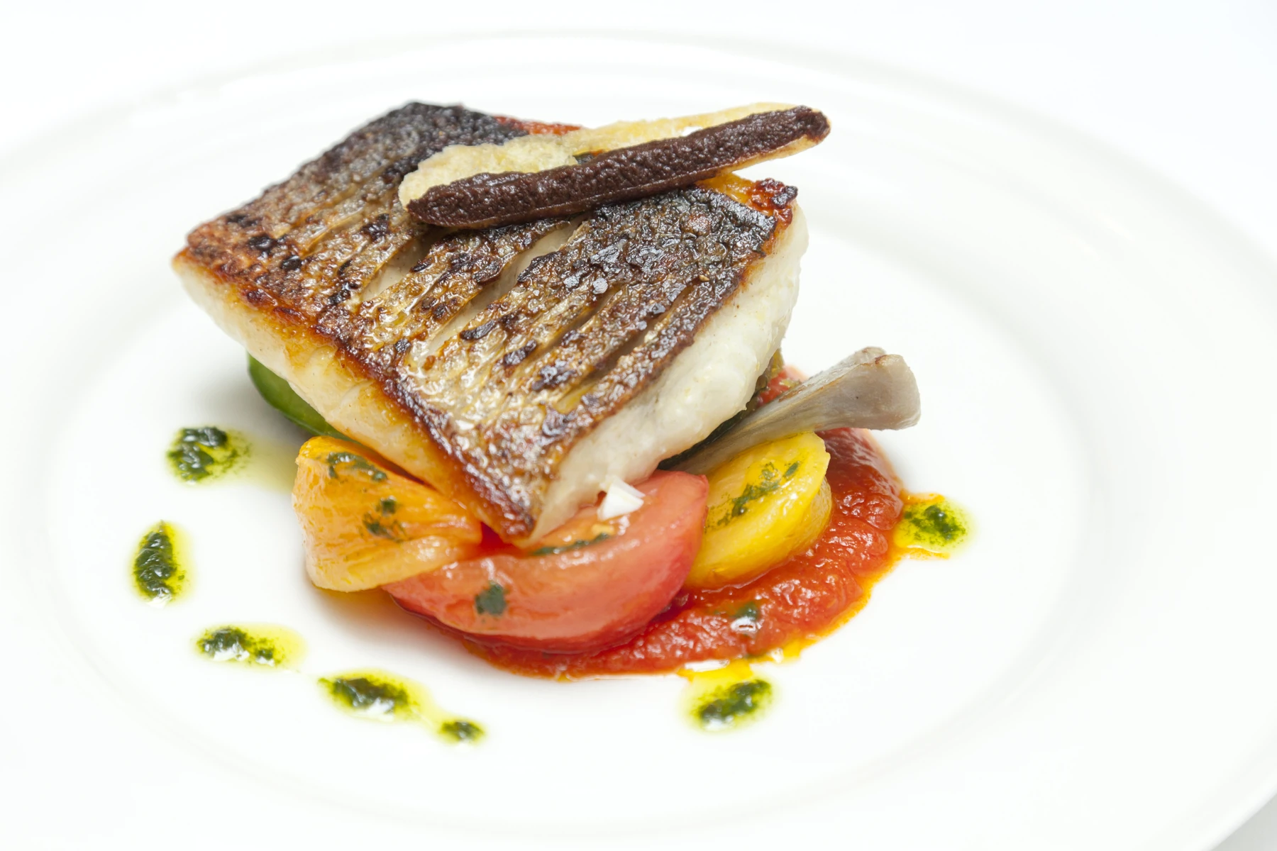 Griddled sea bass with stuffed courgettes, tomatoes, olives and basil