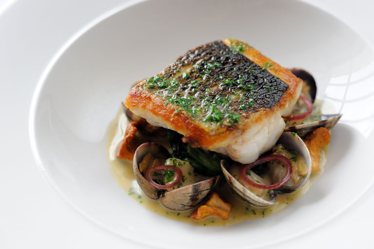 Pan-fried sea bass, butter spinach, clams, poached cod cheeks and fish sauce