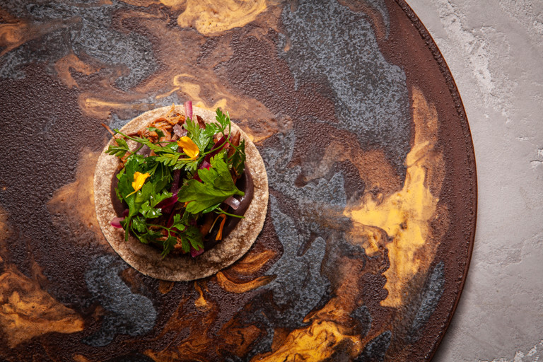 Churrasco (barbecued) lamb breast, black bean feijoada and cassava tacos
