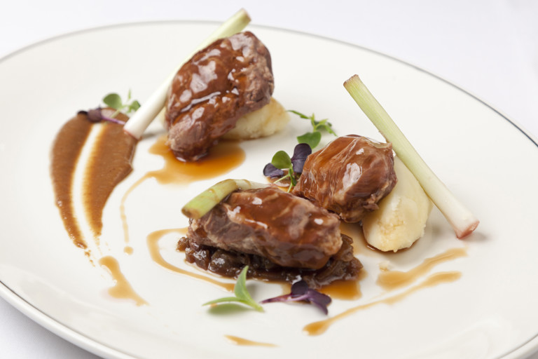 Braised pork cheeks with baby leeks, sultana ragu, mash and caraway jus