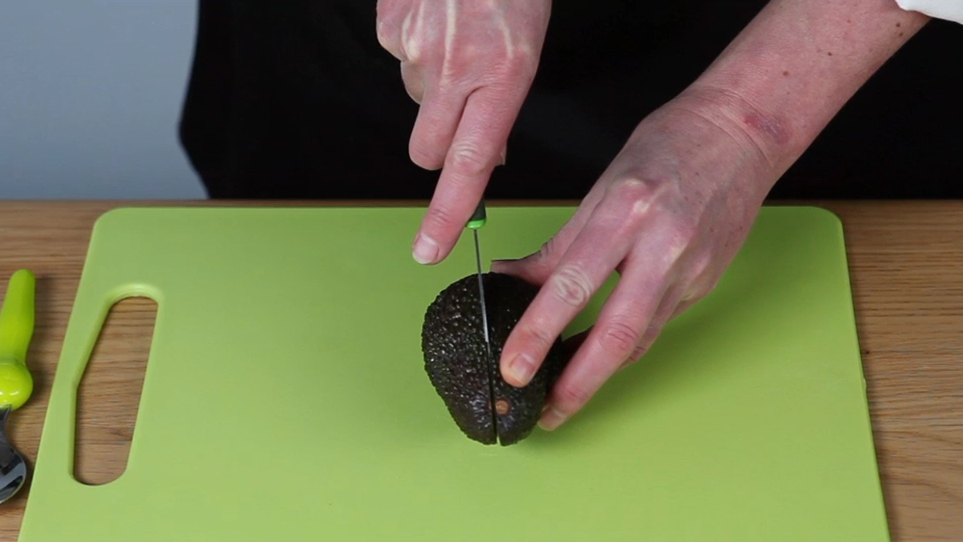 Man Removing a Pit from an Avocado Stock Photo - PixelTote