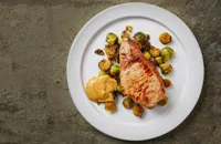 Pork chop with anchovy buttered sprouts and peach mustard