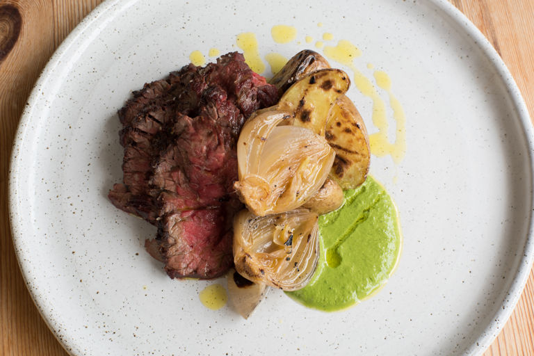 Barbecued bavette steak with green sauce, IPA-braised onions and barbecued potatoes