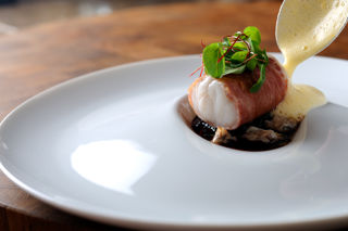 Monkfish wrapped in Parma ham, with red wine jus, lemon sabayon and cockles