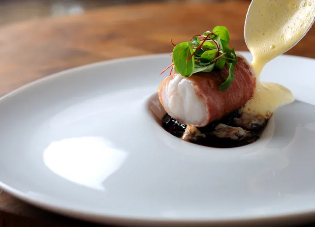 Monkfish wrapped in Parma ham, with red wine jus, lemon sabayon and cockles
