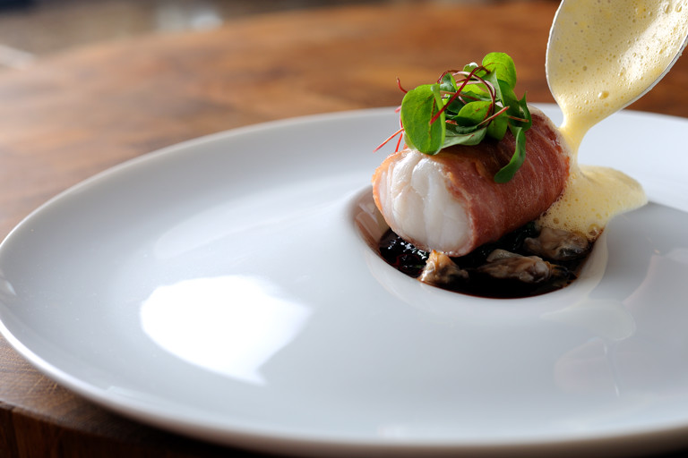 Monkfish wrapped in Parma ham, with red wine jus, lemon sabayon and cockles