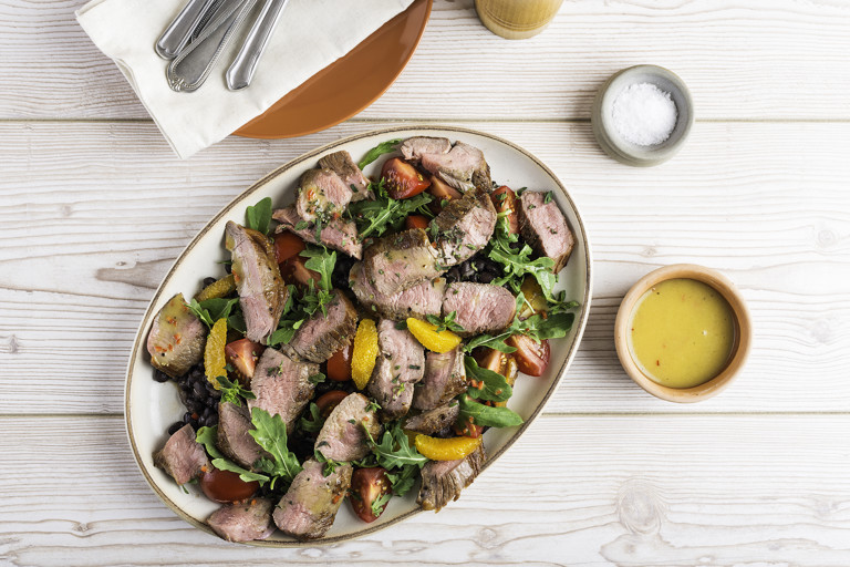Warm salad of slice lamb leg steak, tomato and black beans with a chilli and orange dressing