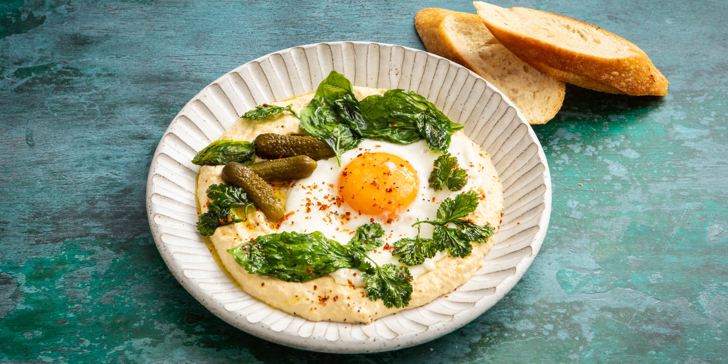 https://media-cdn2.greatbritishchefs.com/media/hagdckfa/hummus-with-olive-oil-fried-eggs-and-summer-herbs-3.whqc_1426x713q80.jpg
