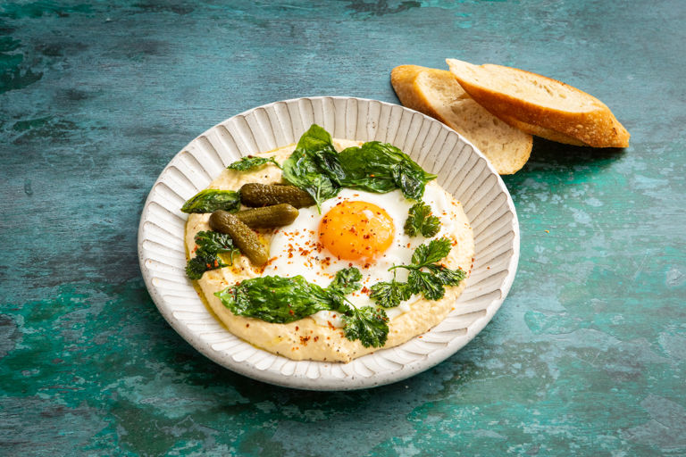 Hummus with olive oil fried eggs and summer herbs