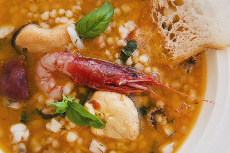Seafood soup with fregula, basil and citrus