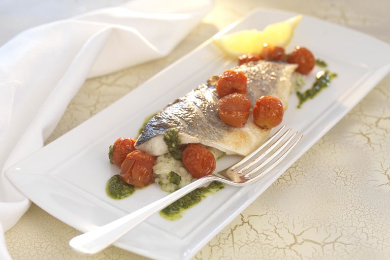 Grilled fillets of sea bass with herb risotto, roasted cherry tomatoes and pesto