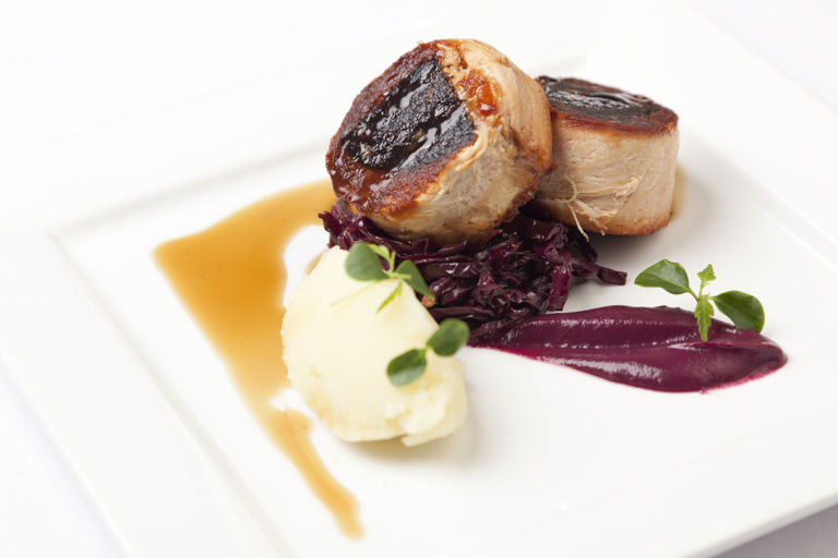 Confit belly of pork stuffed with black pudding with braised red cabbage, mash and cider jus