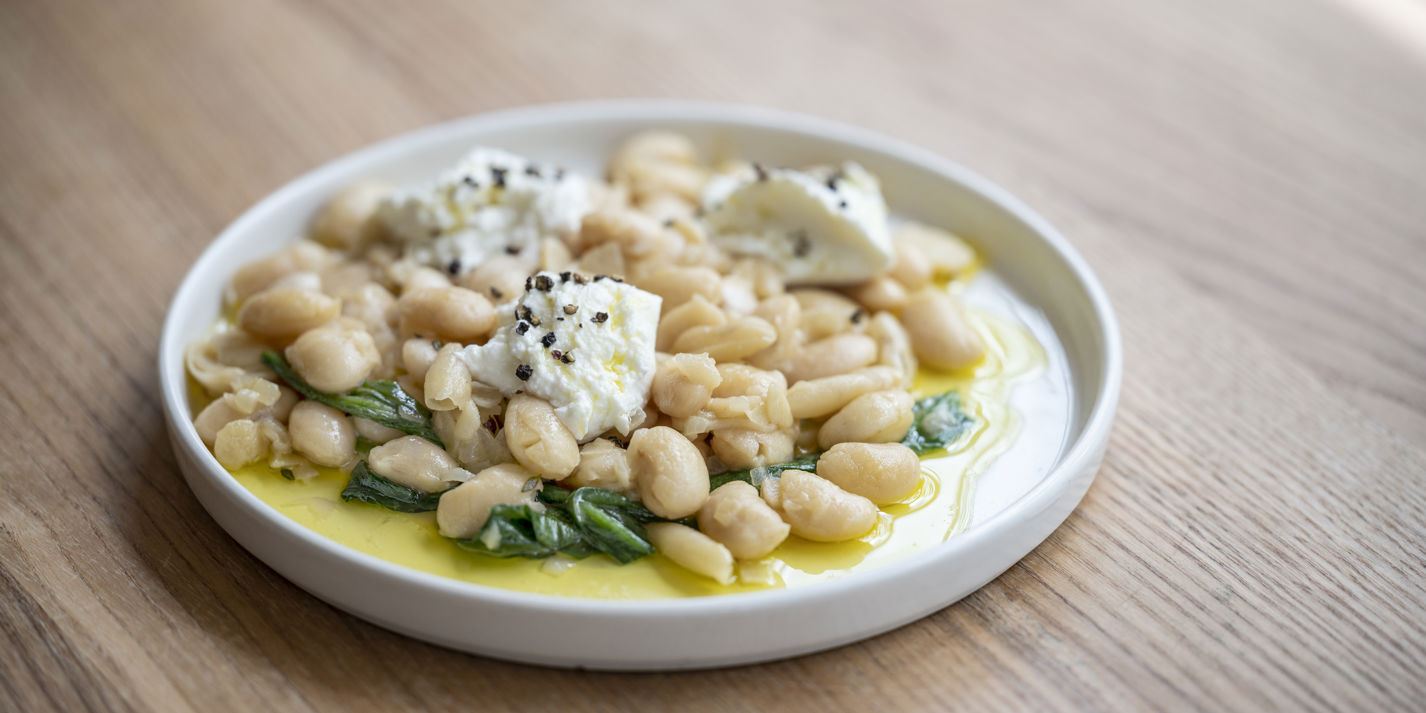 Braised butter beans with wild garlic and goat's curd