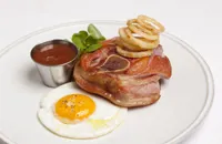 Osso buco of gammon with gooseberry ketchup, fried duck egg and crispy pickled onion rings