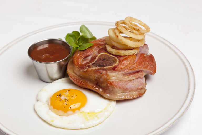 Osso buco of gammon with gooseberry ketchup, fried duck egg and crispy pickled onion rings