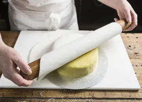 Fold the sugar paste over the rolling pin and lay onto the cake