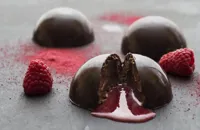 Chocolate mousse domes with raspberry coulis centre