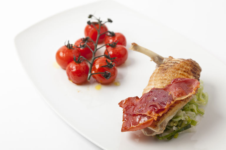 Grilled guinea fowl breast with roasted vine tomatoes and crispy ham