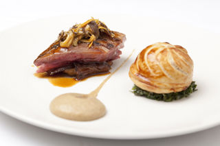 Roast wood pigeon with pithivier of leg, creamed curly kale and roast Jerusalem artichokes