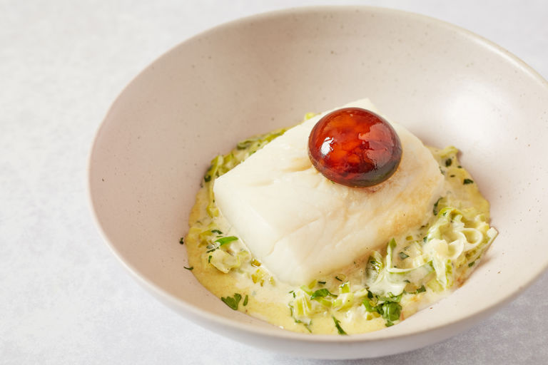 Poached haddock with stewed leeks, soy-cured egg yolks and curry dressing