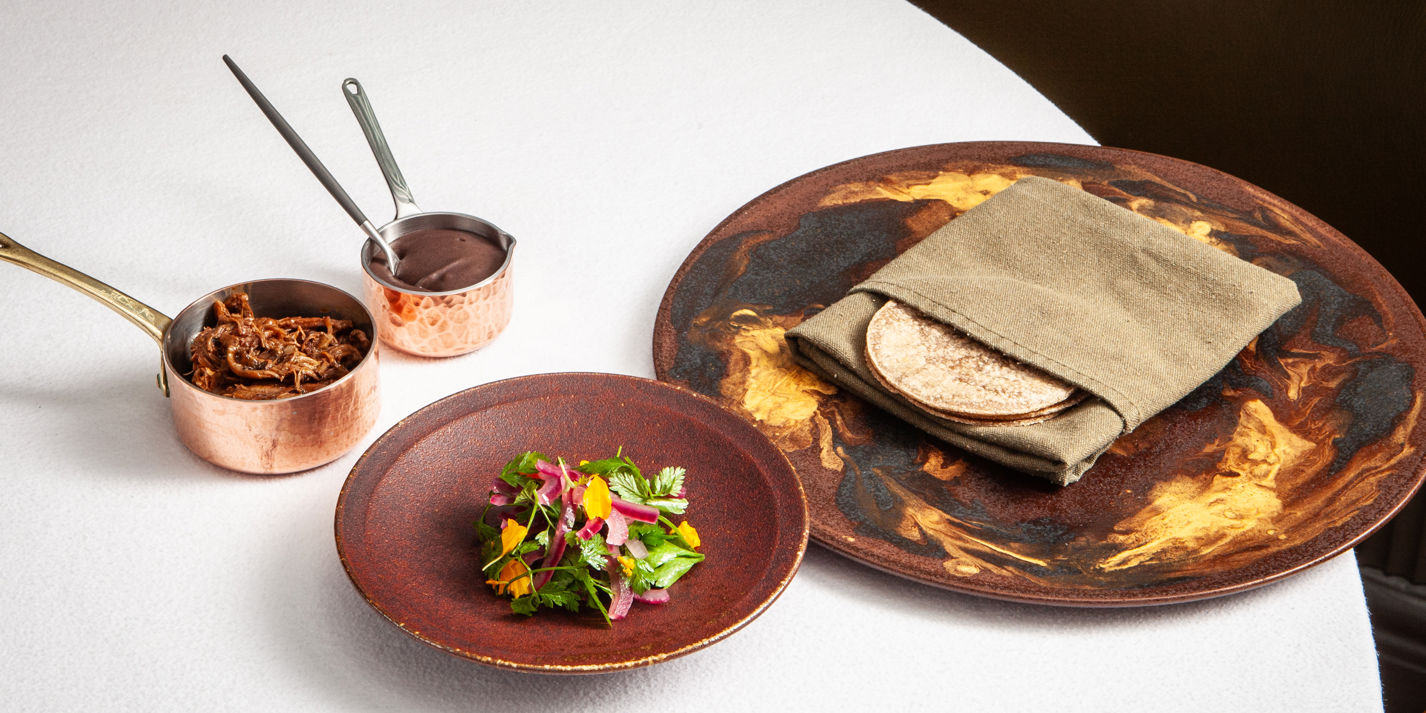 Churrasco (barbecued) lamb breast, black bean feijoada and cassava tacos