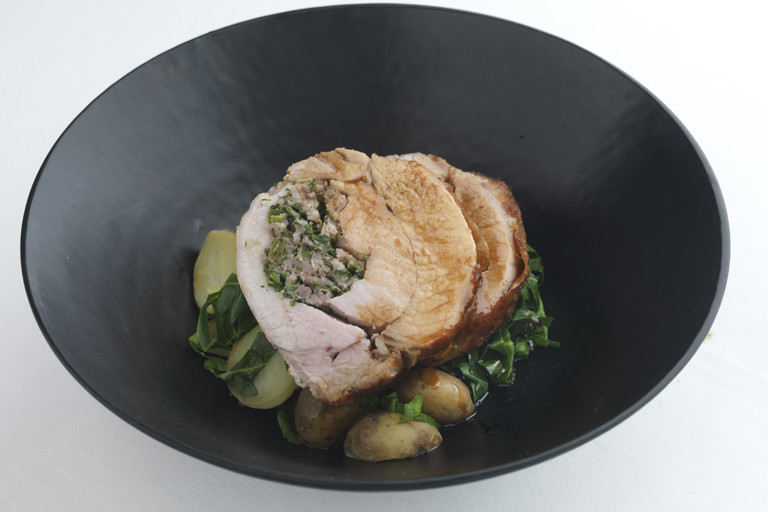 Herb-stuffed pork loin with spring greens and Jersey Royals