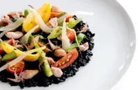 Risotto nero with sautéed squid and tomatoes