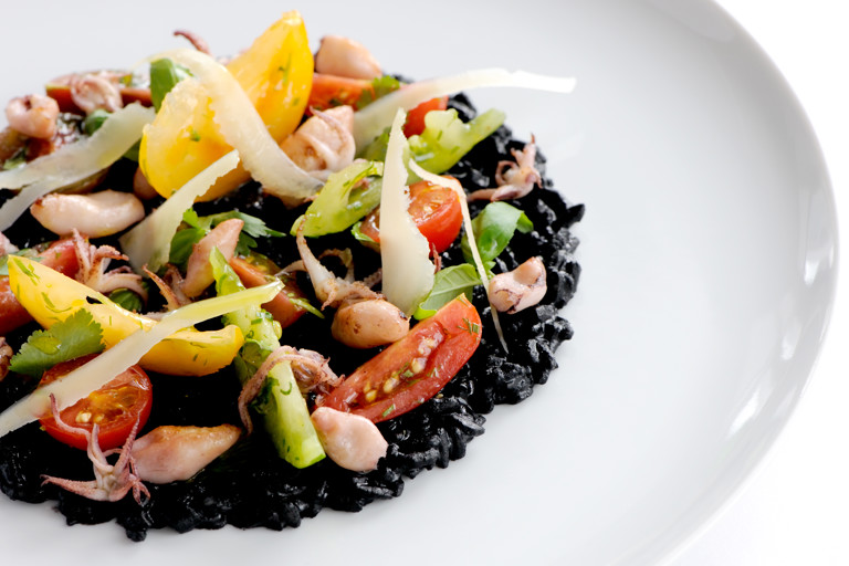 Risotto nero with sautéed squid and tomatoes